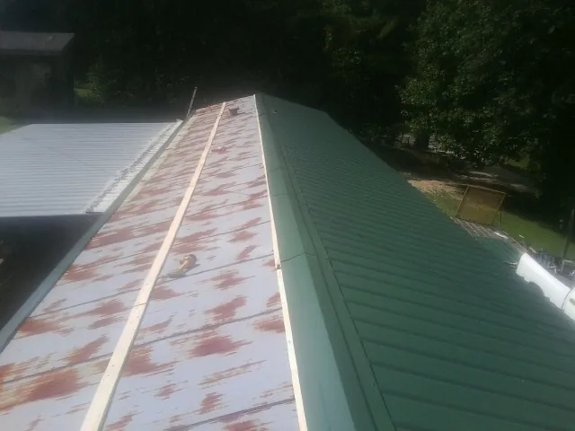 Old rusted panels beside newly installed green metal roofing — Wind Damage Roof Repair by Roofing Brothers in Luthersburg