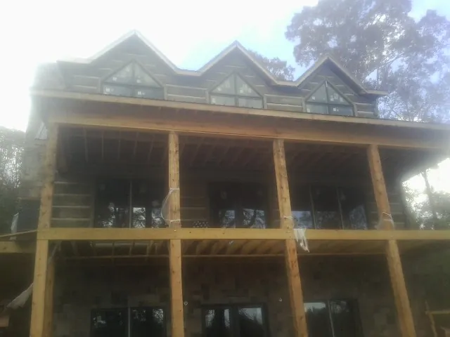Dormers and porch framing on a large log home under construction — Roof Coating work by our crew in Luthersburg