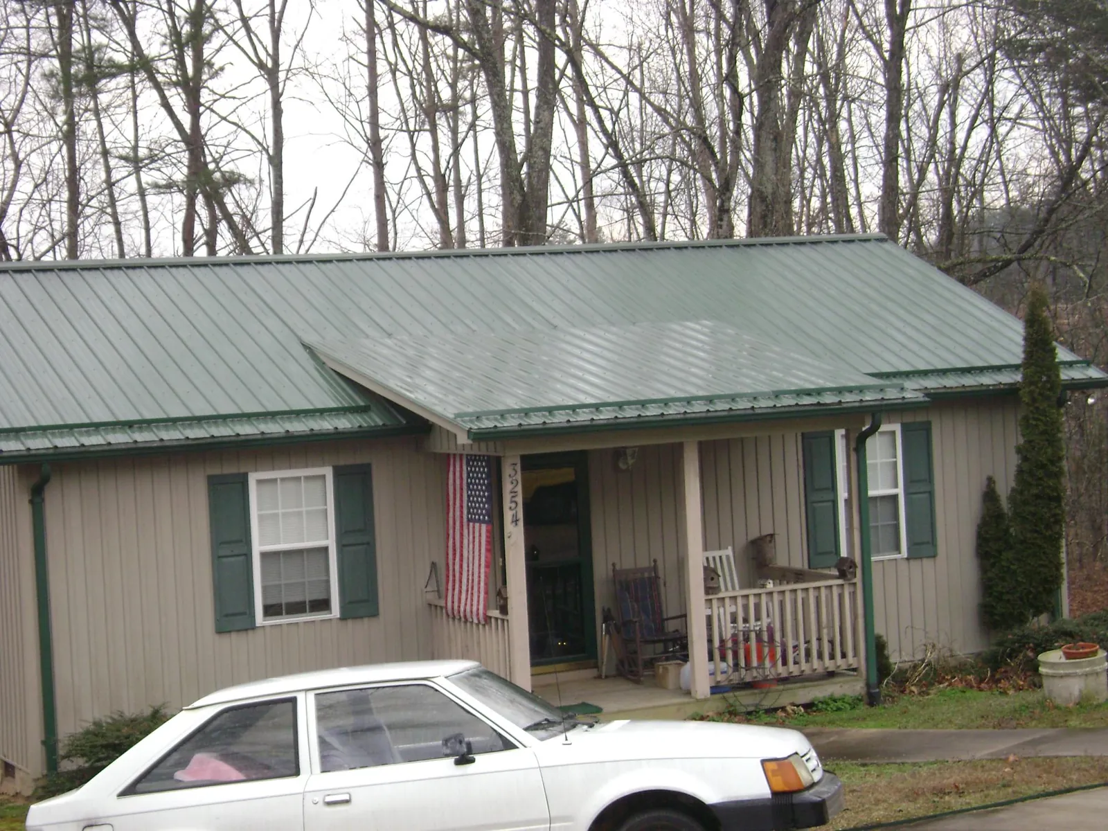 Green metal roof and front porch on a tan sided cottage in Luthersburg