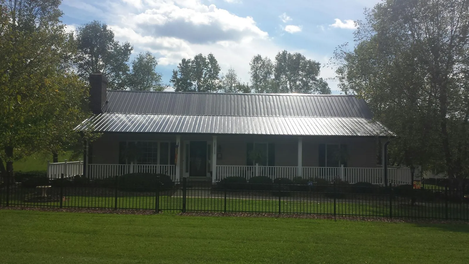 Gray metal roof on a brick ranch with a full width front porch — Gutter Guard Installation work by our crew in Luthersburg