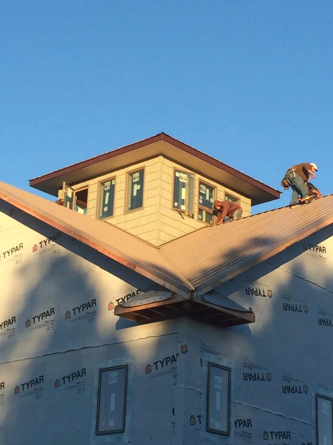 Roofers working around a rooftop cupola on a new metal roof at sunset — Roof Waterproofing in Luthersburg by Roofing Brothers